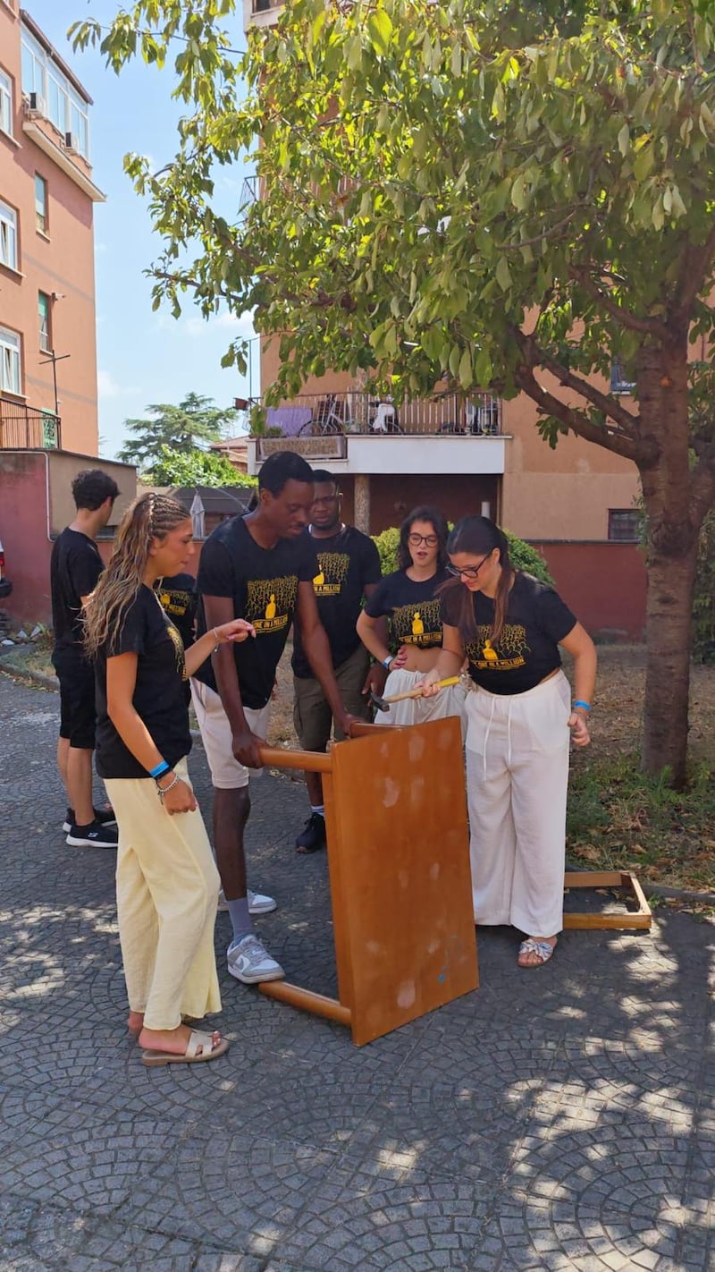 Des jeunes adultes seuls travaillent ensemble au démontage de meubles lors d'un projet de service à la Casa Scalabrini 634 à Rome, en Italie.
