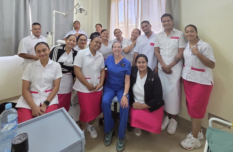 Kathleen Young, en bleu, sourit avec ses etudiants en medecine dentaire dans la clinique de l'hopital Viola a Nuku'alofa, aux Tonga, en mars 2026.