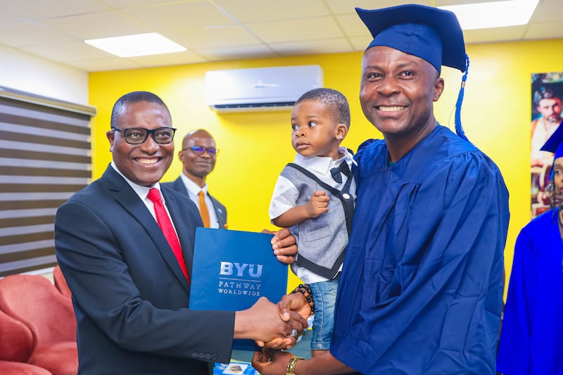 Elder Adeyinka Ojediran serre la main d'un étudiant ayant terminé un programme de BYU-Pathway lors de la cérémonie de fin de programme à Lagos, au Nigeria, le 11 décembre 2025.
