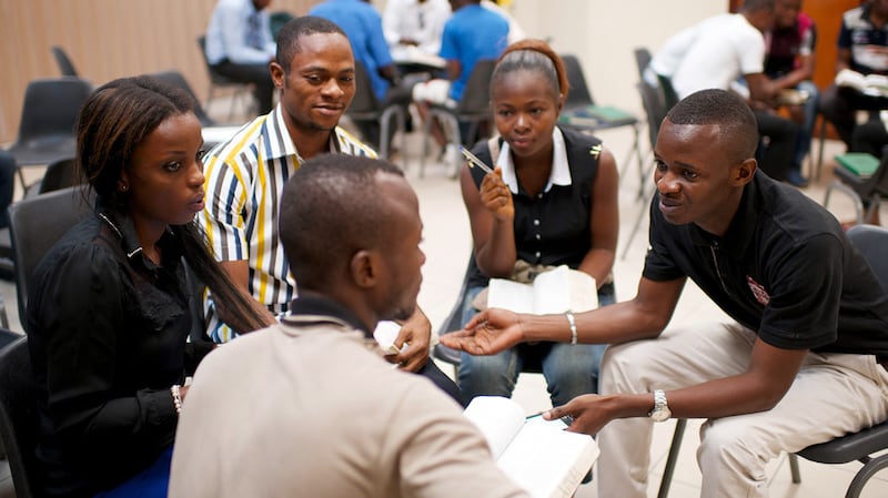 A group of youth in Africa studies and discusses the scriptures together in a seminary class.