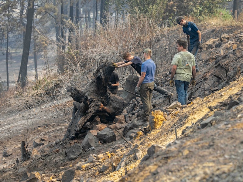 Des jeunes gens et des dirigeants du pieu de Mount Spokane (Spokane, Washington) aident à déblayer les débris dans un quartier endommagé par des feux de forêt à Spokane (Washington), le lundi 3 août 2026.