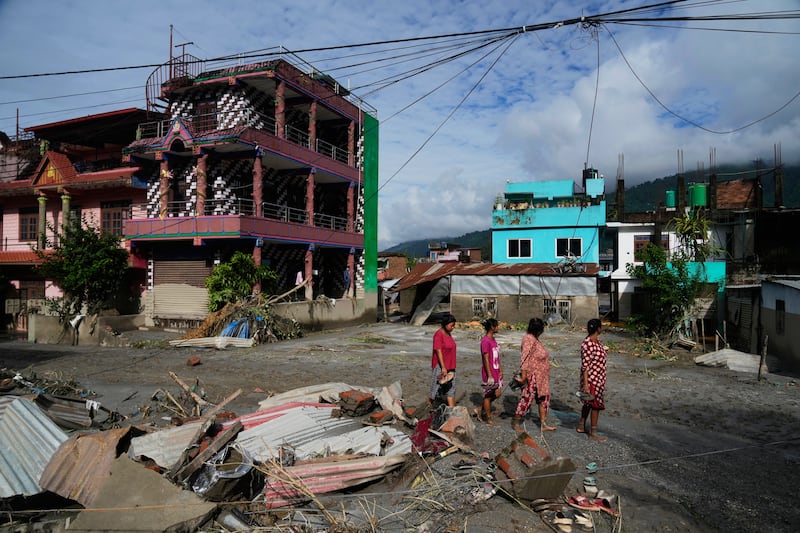 Des personnes passent devant les dégâts causés par des inondations éclair à Devighat, dans le district de Nuwakot au Népal, le jeudi 27 août 2026.