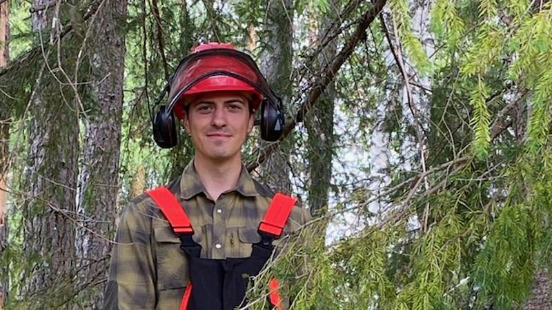 Frère Claus Andersen porte un casque et tient une tronçonneuse tout en abattant des arbres près d'Oslo, en Norvège.