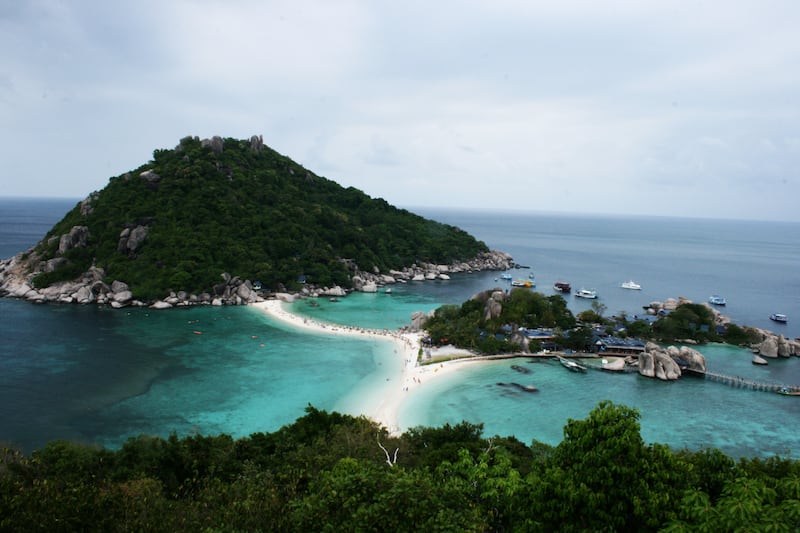 Une vue panoramique en plongée d'îles tropicales reliées par un banc de sable blanc dans une mer turquoise.
