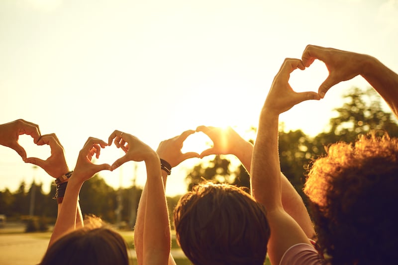Mains d'un groupe d'amis formant un cœur devant le coucher du soleil. Concept d'amour, de relations et d'amitié
