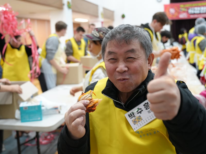 Un homme sourit en participant aux efforts de préparation et de don de 100 boîtes de kimchi à Séoul, en Corée du Sud, en décembre 2024.
