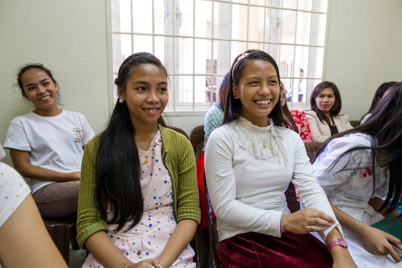Des jeunes filles aux Philippines sont assises ensemble en classe et sourient.