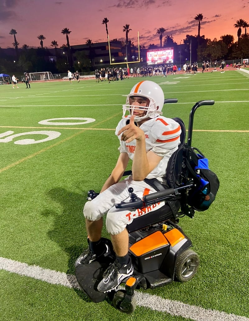 Matthew Cooper porte son uniforme de football américain dans son fauteuil roulant pour un match de son lycée à l'automne 2024.