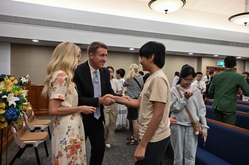Le président général des Jeunes Gens Timothy L. Farnes et son épouse, sœur Linsey Farnes, saluent un jeune homme après une veillée lors d'une affectation de ministère dans des pays d'Asie, du 21 au 31 mai 2026.