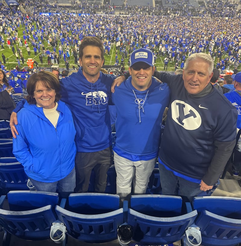 Shawna Edwards, à gauche — compositrice de « The Miracle », un nouvel ajout à Cantiques pour le foyer et l’Église — pose avec son mari, John, et ses deux fils lors d’un match de football américain de l’université Brigham Young à l’automne 2024.