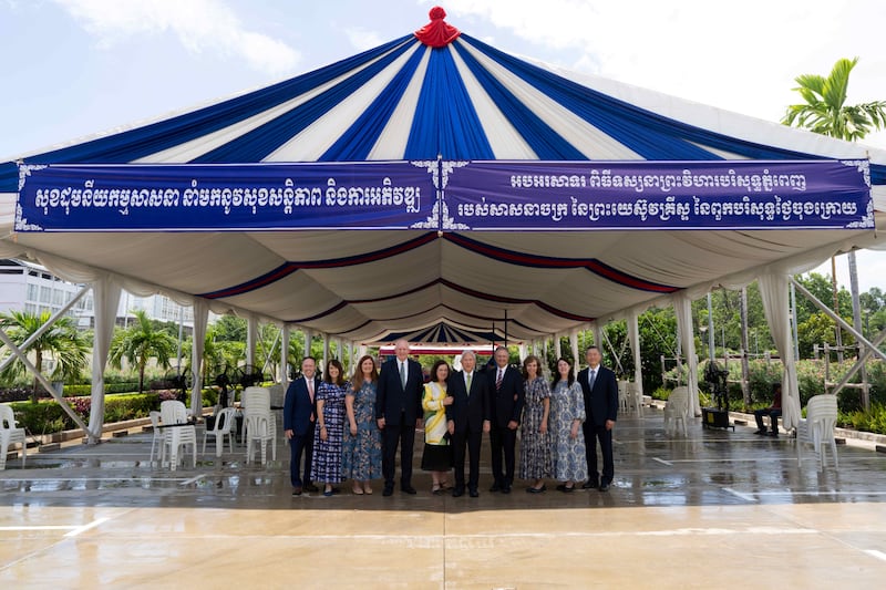 Le frère Gerrit W. Gong et son épouse, la sœur Susan Gong, au centre, se joignent à quatre soixante-dix Autorités générales et à leurs épouses sous une tente fournie par le gouvernement cambodgien pour la première journée des visites guidées du temple de Phnom Penh (Cambodge), le mercredi 12 août 2026. Le panneau indique : « L'unité dans la religion apporte la paix et le développement. Félicitations pour le temple de Phnom Penh (Cambodge) de l'Église de Jésus-Christ des Saints des Derniers Jours. »