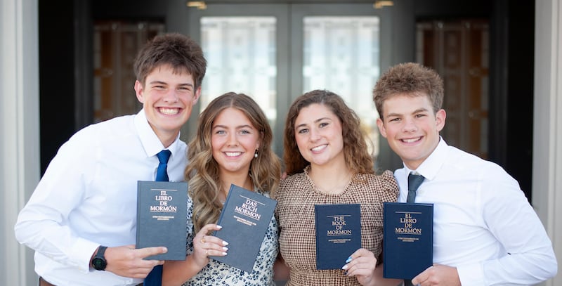 Eli, Elle, Isabel et Isaac Reid, frères et soeurs, brandissent des exemplaires du Livre de Mormon dans les langues respectives qu'ils apprendront en tant que missionnaires.