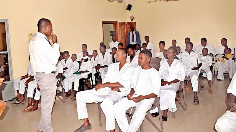 Des candidats au baptême vêtus de blanc attendent dans la chapelle leur tour pour être baptisés dans des fonts baptismaux à l'extérieur, à Bamako, au Mali, le 18 avril 2026.