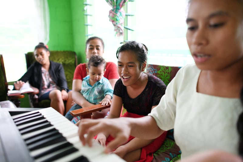 Une famille chante à la maison tandis qu'une fille joue du clavier.