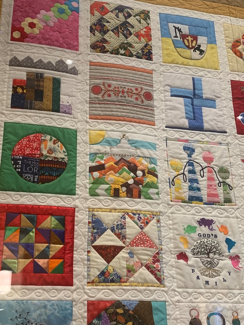 Gros plan montrant des carrés de tissu cousus individuellement dans "La courtepointe familiale" exposée au centre d'accueil des visiteurs de Temple Square, à Salt Lake City, en juin 2026.