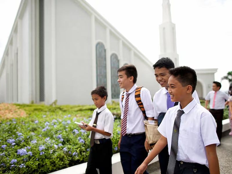 Des jeunes gens marchent devant un temple de l'Eglise de Jesus-Christ des Saints des Derniers Jours.
