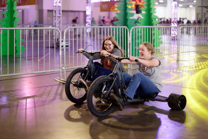 Deux femmes participent à une course de tricycle au Salt Palace Convention Center lors de la conférence 2026 des jeunes adultes seuls de l'interrégion d'Utah, à Salt Lake City, le vendredi 14 août 2026.