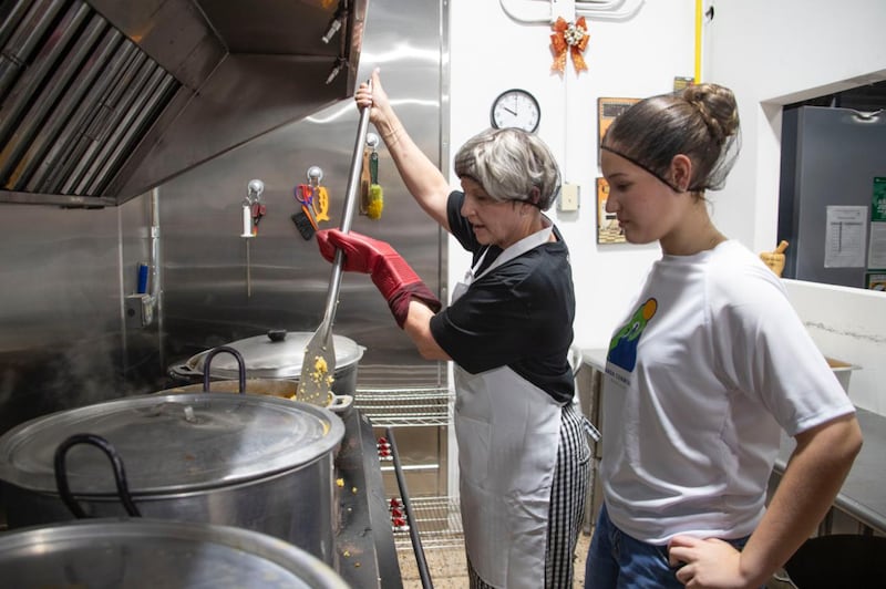 La présidente Emily Belle Freeman remue une grande marmite lors d'une activité de service communautaire à Naguabo, à Porto Rico, le samedi 16 mai 2026.
