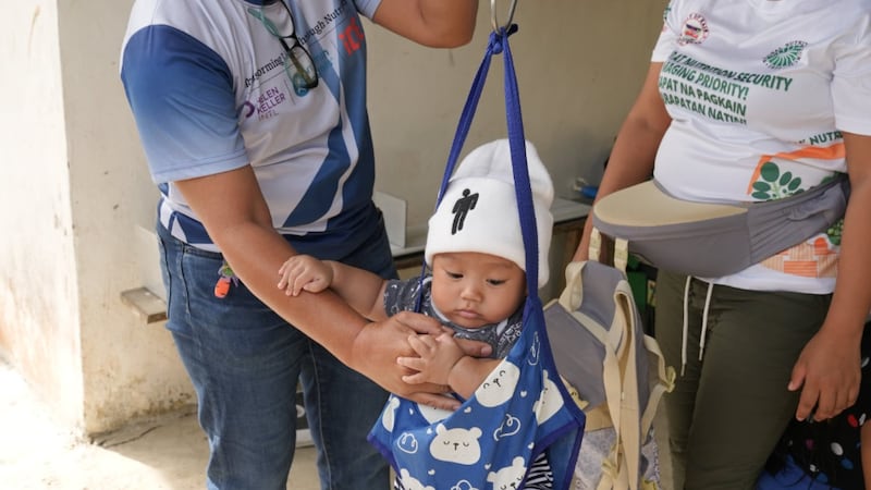 Un enfant est pesé lors d'un dépistage nutritionnel aux Philippines, août 2025.