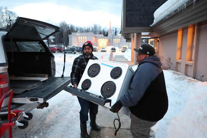 Des membres de l'église baptiste New Hope transportent une cuisinière jusqu'à leur camion à Anchorage (Alaska).