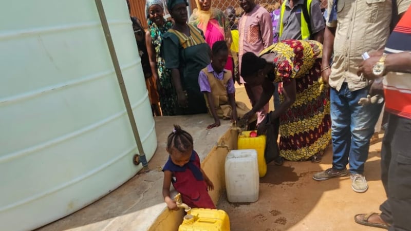 Des résidents de la communauté remplissent des récipients d'eau potable après une cérémonie de remise dans l'ouest de Freetown, en Sierra Leone, le 3 avril 2026.