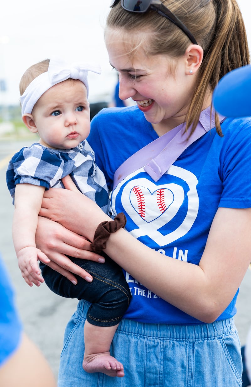 Une bénévole marque une pause pour prendre une photo avec sa petite sœur lors d'une soirée JustServe au match des Royals de Kansas City à Kansas City, Missouri, le 9 avril 2026.