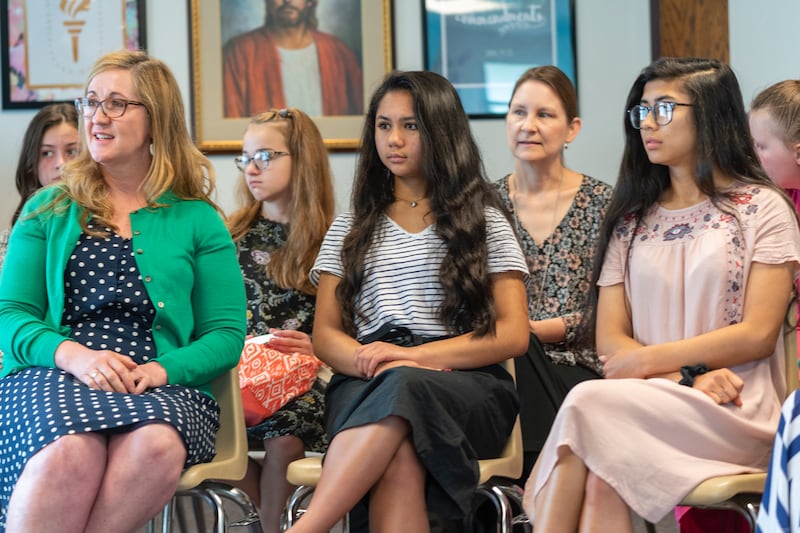 Des jeunes filles et leurs dirigeantes écoutent pendant une leçon le dimanche.
