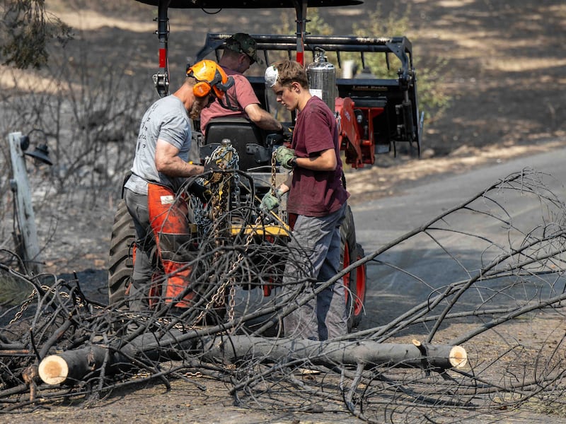Des jeunes gens et des dirigeants du pieu de Mount Spokane (Spokane, Washington) aident à déblayer les débris d'un quartier endommagé par des feux de forêt à Spokane (Washington), le lundi 3 août 2026.