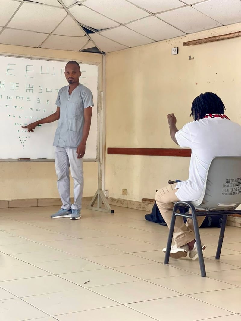 Adolphus Togbah, à gauche, fait un examen de la vue dans une clinique gratuite installée dans une école au Liberia.