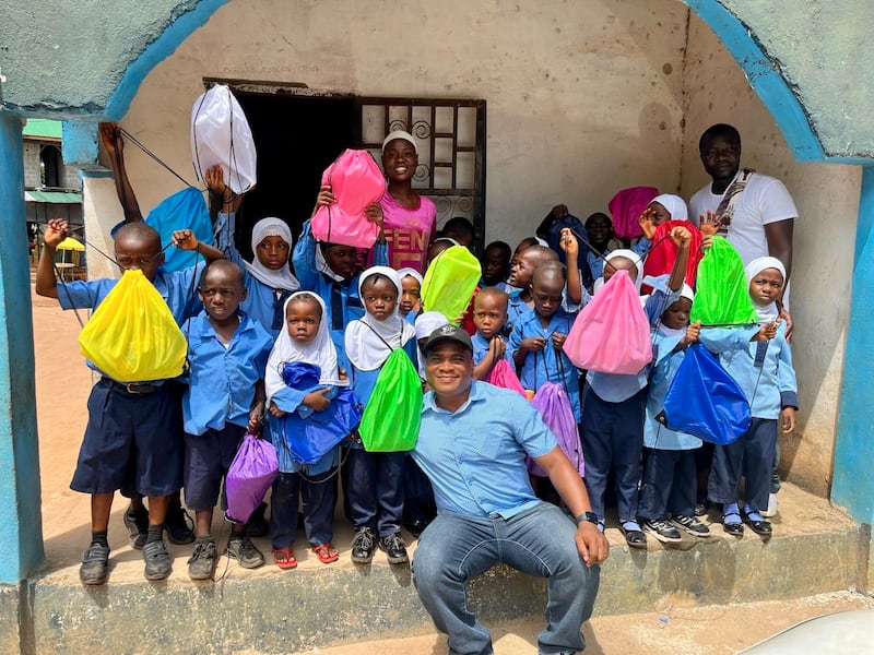 Konrad Barjuah, au centre, remet des kits scolaires à une école au Liberia.