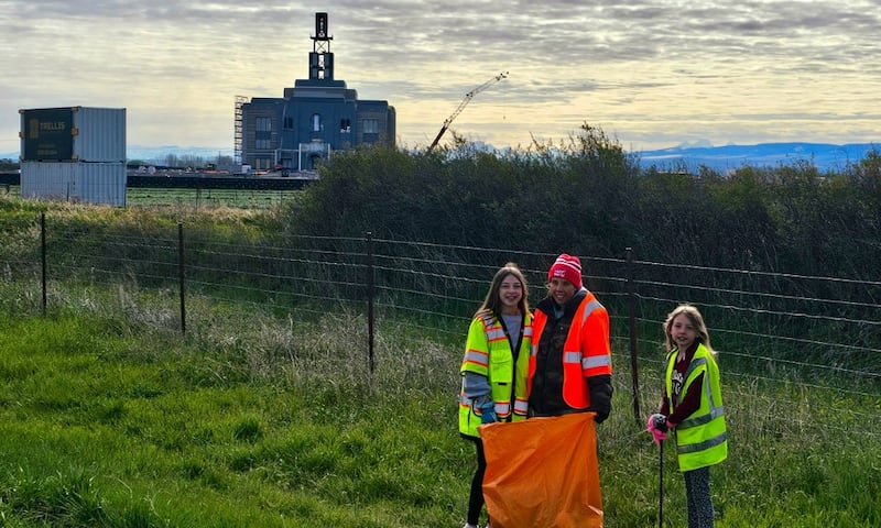 Des jeunes filles ramassent des dechets le long de l'autoroute pres de Rexburg, en Idaho, dans le cadre de la Journee mondiale du service des jeunes, le samedi 25 avril 2026. Le temple de Teton River, en Idaho, est en construction a l'arriere-plan.
