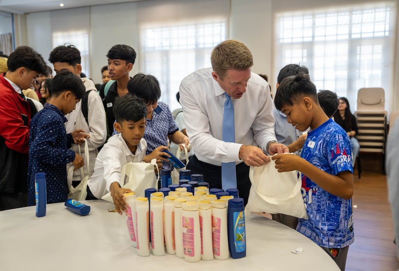 Le président général des Jeunes Gens Timothy L. Farnes aide un jeune lors d'un projet de service visant à assembler plus de 200 sacs de soins pour un orphelinat à Phnom Penh, au Cambodge, en mai 2026.