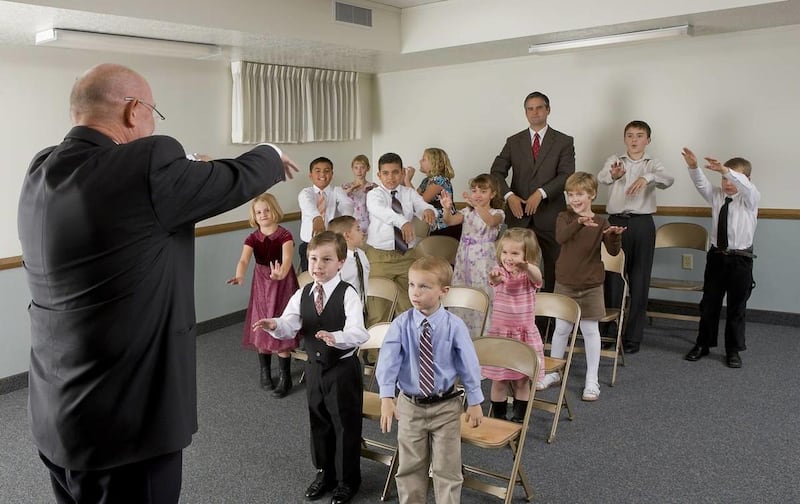 Les enfants de la Primaire suivent la dirigeante de la musique pendant la période de chant.