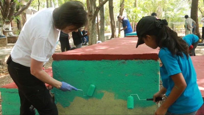 La présidente Susan H. Porter aide une fillette à peindre des parties d'un parc public lors d'une activité de service à Tuxtla Gutiérrez, Chiapas, Mexique, en mai 2026.