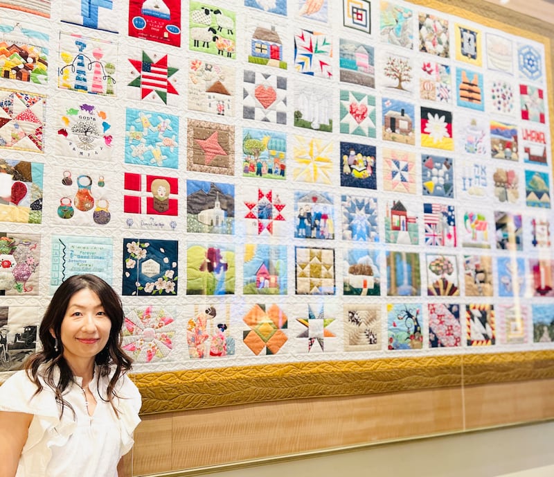 Sachiko Aldous se trouve près de l'exposition intitulée "La courtepointe familiale" au centre de visiteurs de Temple Square, à Salt Lake City, en juillet 2026.