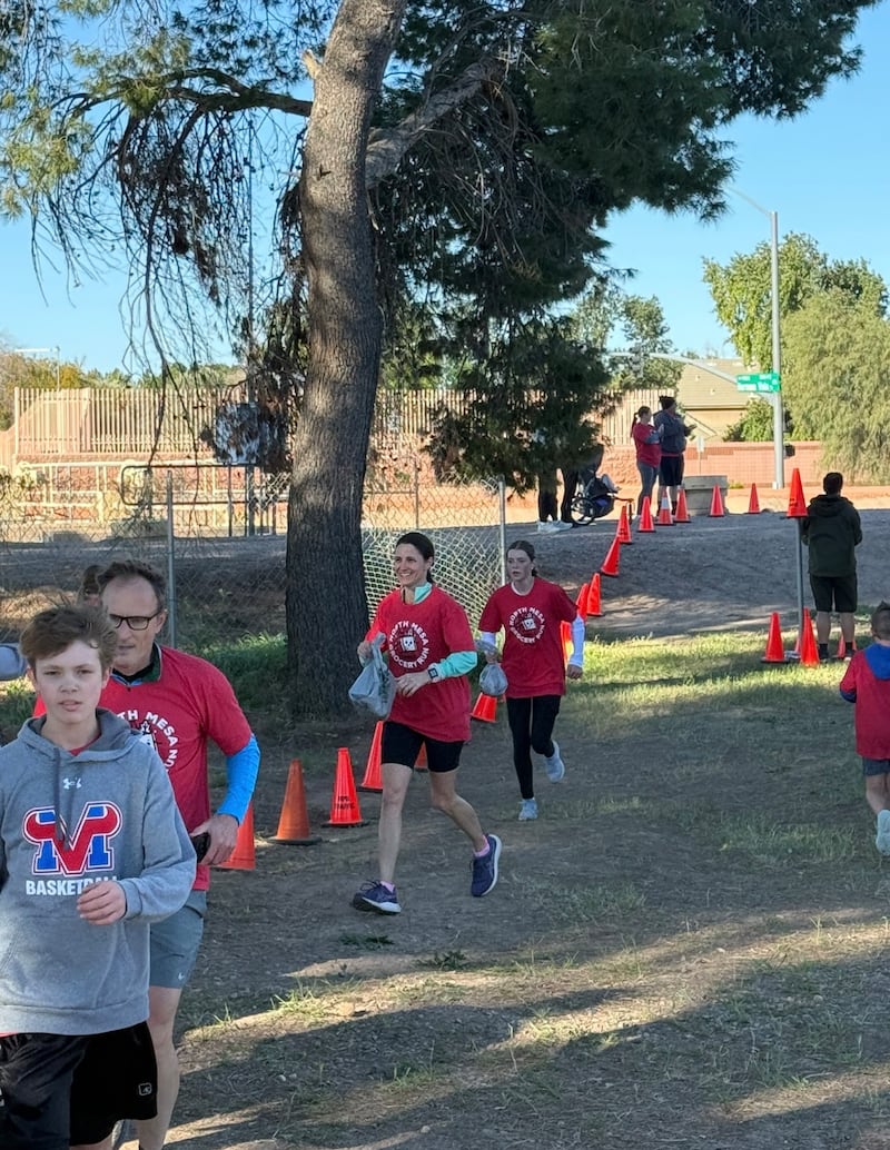 Les participants courent vers la ligne d'arrivée avec des sacs d'épicerie remplis de nourriture donnée lors de la deuxième édition annuelle de la course d'épicerie de Northeast Mesa à Mesa, Arizona, le 21 février 2026.