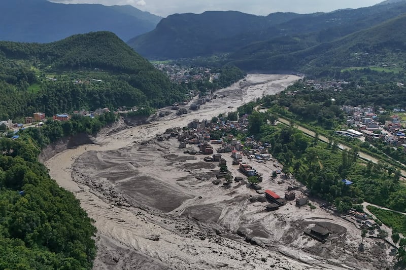 Des maisons endommagées se dressent dangereusement près des berges en crue et encombrées de débris de la rivière Trishuli après des inondations soudaines dans le district de Nuwakot, au Népal, le mercredi 26 août 2026.