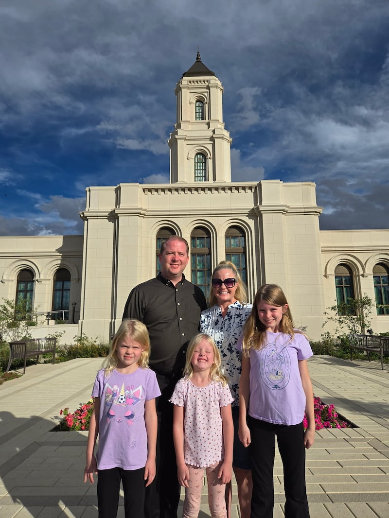 Luke Hopkin, en arrière-plan à gauche, et son épouse, Sara Hopkin, posent avec leurs filles Kapree, Violet et Alyce Hopkin devant le temple de Cody (Wyoming) en 2026.