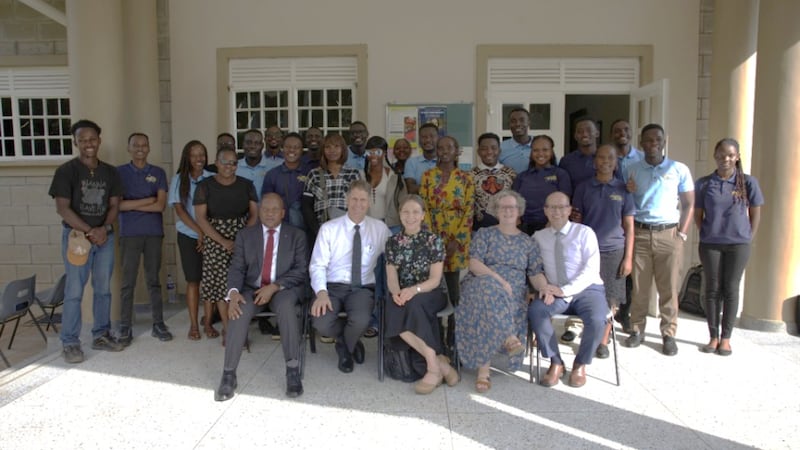 Frère Frederick Kamya, frère Carl B. Cook, sœur Lynette Cook, sœur Isabelle Giraud-Carrier et frère Christophe Giraud-Carrier prennent une photo avec les dirigeants des jeunes adultes seuls du pieu de Kampala Ouganda Nord, le 17 mars 2026.