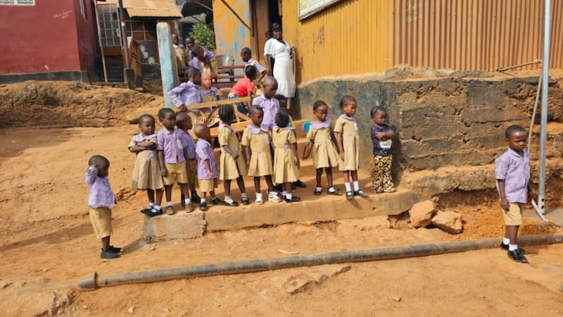 Des écoliers observent la scène lors d'un don d'un forage d'eau à New England Ville, dans l'ouest de Freetown, en Sierra Leone, le 3 avril 2026.
