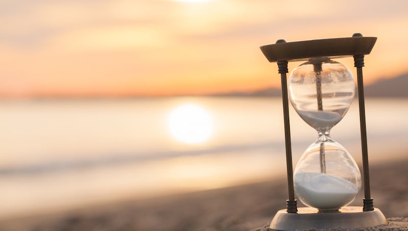 Un sablier est posé sur la plage au lever du soleil.