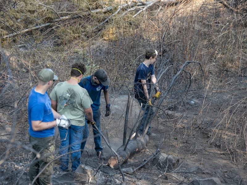 Des jeunes gens et des dirigeants du pieu de Mount Spokane (Spokane, Washington) aident à déblayer les débris d'un quartier endommagé par des feux de forêt à Spokane (Washington), le lundi 3 août 2026.