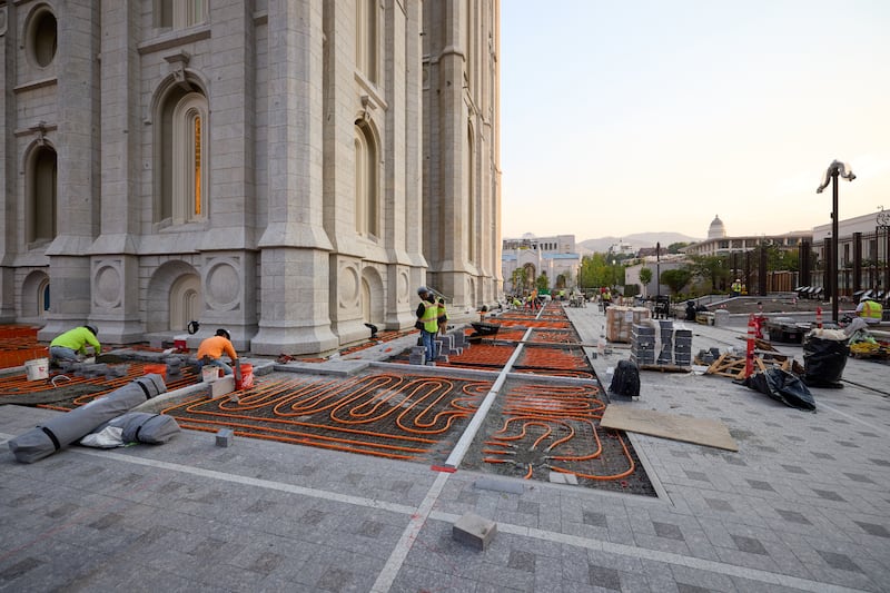 Des équipes installent un pavage en pierre sur des tubes de fonte de neige à l'extérieur du temple de Salt Lake à Salt Lake City le mardi 23 juin 2026.