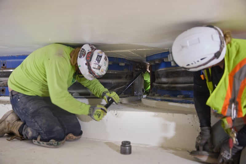 Des équipes retirent les boulons de l'une des plaques d'un isolateur de base situé à 20 pieds sous le temple de Salt Lake à Salt Lake City le jeudi 25 juin 2026.