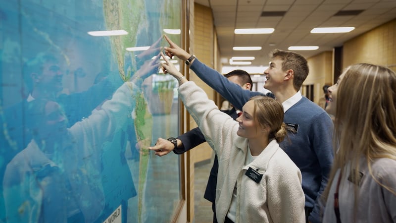 Des missionnaires indiquent leur mission assignée sur une carte du monde lors du tournage d'une nouvelle vidéo au centre de formation missionnaire de Provo.