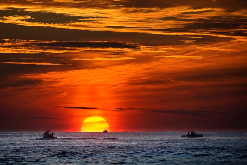 Le soleil se lève sur des bateaux de pêche dans l'océan Atlantique, le 8 sept. 2022, au large de Kennebunkport, dans le Maine.
