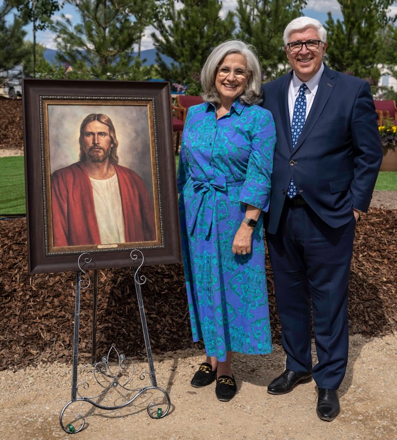Elder José A. Teixeira et sœur Filomena Teixeira prennent la pose pour une photo près d'un tableau du Sauveur lors de la cérémonie de la première pelletée de terre du temple de Missoula (Montana).