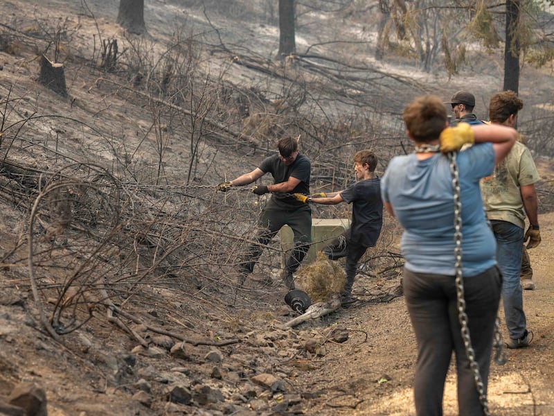 Des jeunes gens et des dirigeants du pieu de Mount Spokane (Spokane, Washington) aident à déblayer les débris dans un quartier endommagé par des feux de forêt à Spokane (Washington), le lundi 3 août 2026.