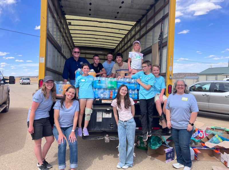 Des enfants, des jeunes et des adultes à Albuquerque, au Nouveau-Mexique, sourient avec un camion chargé d'eau issue de dons pour aider face à la pénurie d'eau dans la communauté de To’hajilee, le 6 mai 2026.