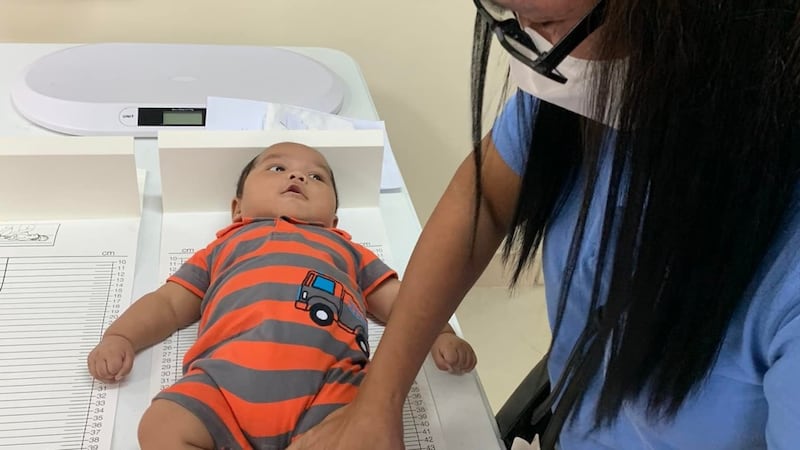 Un professionnel de la santé mesure la taille d'un bébé lors d'un dépistage au centre de pieu de Sipocot, aux Philippines, le 21 juillet 2022.